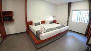 A hotel room with a large bed, a bedside table, a nightstand, a wall-mounted TV, and a window with curtains. - Hotel Records (Phnom Penh)