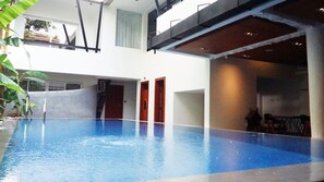 An indoor swimming pool with a clear view of the surrounding area, including a staircase and a door leading to another room. - Hotel Records (Phnom Penh)