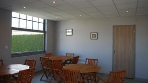 A room with a large window, a door, and several wooden tables and chairs. - Mobil-Home 4 people comfort n°27 (Gonneville en Auge)