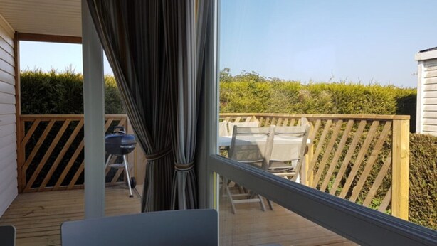 A deck with a wooden railing, a grill, and outdoor furniture. - Mobil-Home 4 people comfort n°27 (Gonneville en Auge)