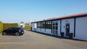 A building with a red roof, large windows, and a sign that reads "Accueil". - Mobil-Home 4 people comfort n°27 (Gonneville en Auge)