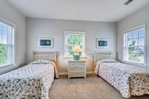 A bedroom with two beds, a nightstand with a lamp, and two framed pictures on the wall. - Sunset views-Close to pool, Pickleball and Tennis Courts (Duck)