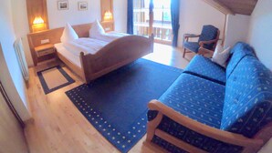 Een slaapkamer met een bed, een slaapbank, een stoel en uitzicht op de omgeving.