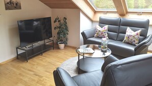 Een moderne woonkamer met een flatscreen televisie, een leren bank en een glazen salontafel.