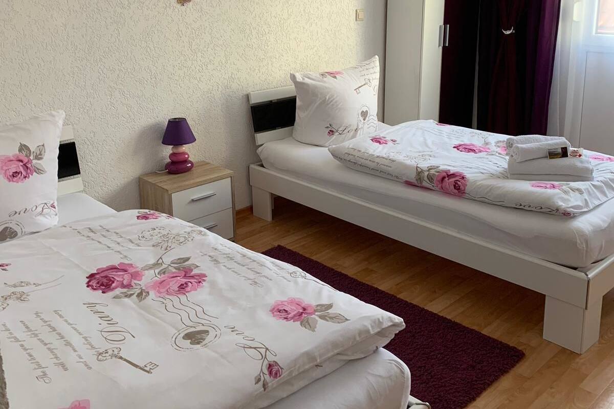 A bedroom with two single beds, a wardrobe, a bedside table with a lamp, and butterfly wall decorations.