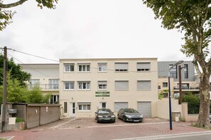 A multi-story residential building with a beige facade, two cars parked in front, and a gated entrance. - Studio 25 sqm - 90, av. Gal de Gaulle (Clamart)
