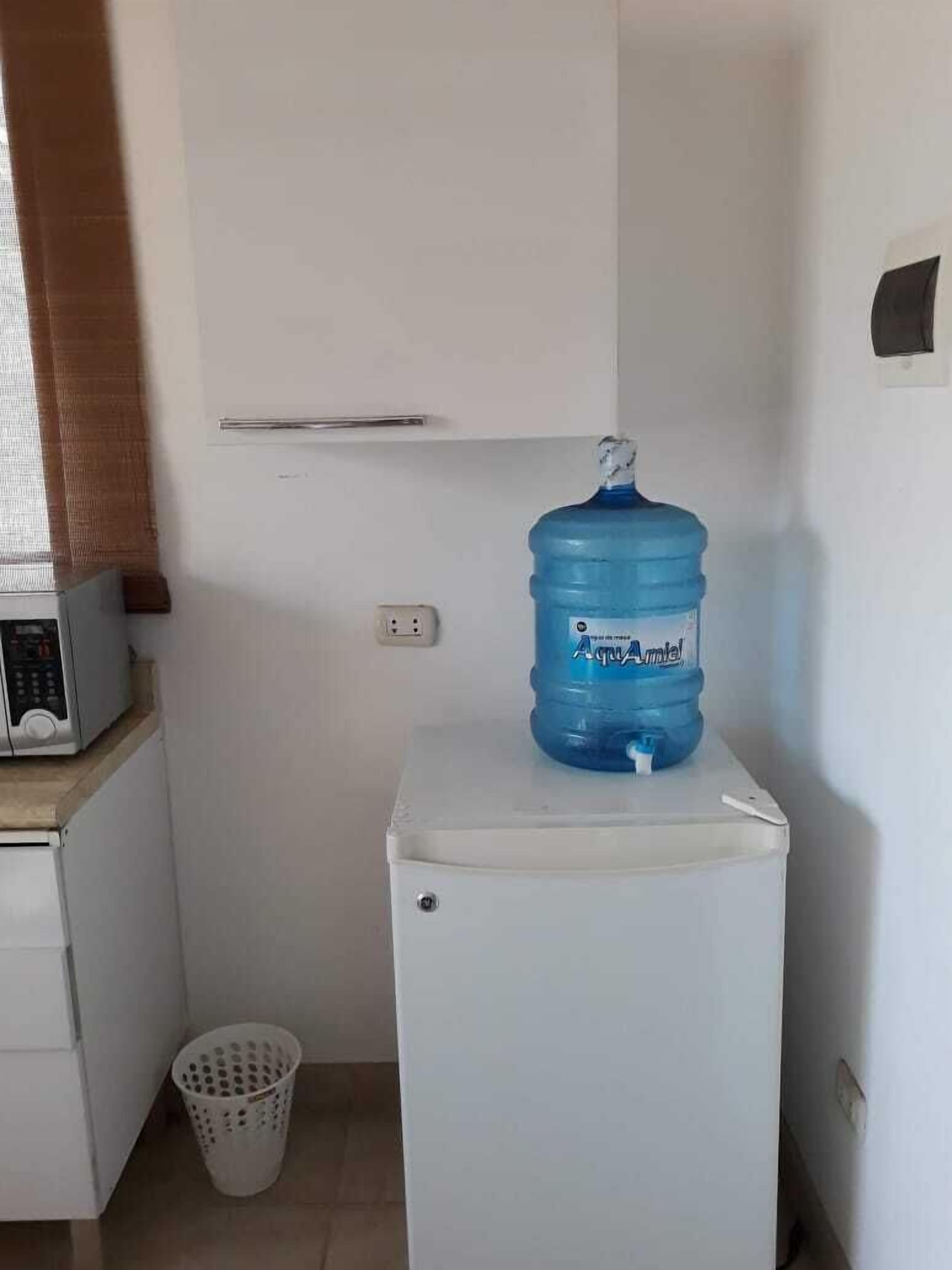 Une petite cuisine équipée d’un four à micro-ondes, d’un distributeur d’eau et d’une petite poubelle.