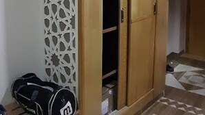 A room with a wooden wardrobe, a patterned partition, and a bench with bags. - Hotel Souf (El Oued)