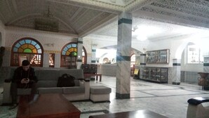 A lobby with a marble floor, a sofa, a coffee table, and a pillar. - Hotel Souf (El Oued)