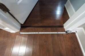 A wooden floor with a measuring tape laid across it.