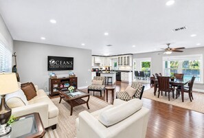 A spacious living area with a dining table, sofas, and a kitchen in the background.
