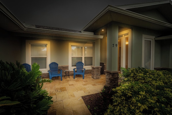 A house exterior with a covered patio, two blue chairs, and a number 79 on the door.