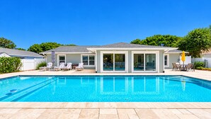 Une piscine résidentielle dotée d’un espace patio, de chaises longues et d’un coin salon abrité.