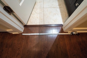 A measuring tape on a wooden floor, indicating a space between two walls.