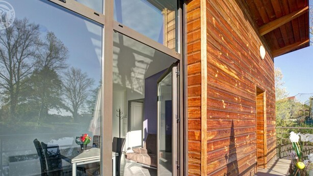 A modern wooden cabin with a glass door leading to a patio area. - Unique cabin on pond, 2 to 4 ppl, pets allowed (Veauchette)