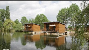 Two wooden cabins with outdoor seating, floating on a calm lake, surrounded by trees. - Unique cabin on pond, 2 to 4 ppl, pets allowed (Veauchette)