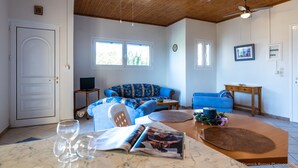 A living room with a blue sofa, a wooden coffee table, and a ceiling fan. - Beach Front Villa Gousetis (Zakynthos)