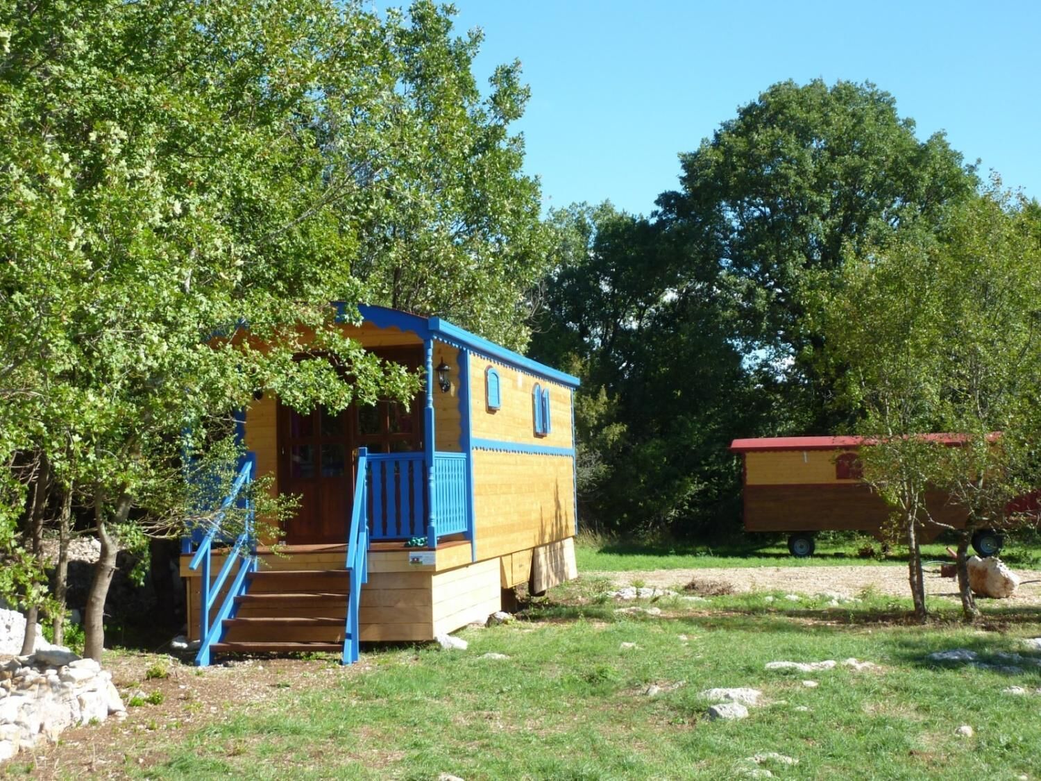 Un piccolo chalet in legno con rivestimenti blu, un portico e una scala.