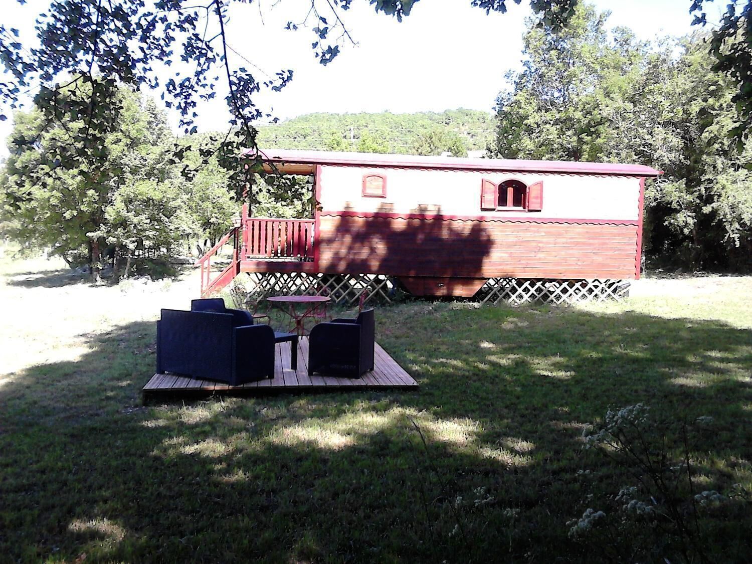 Une cabane en bois à l’extérieur rouge, dotée d’une terrasse et d’une table de pique-nique avec des chaises.
