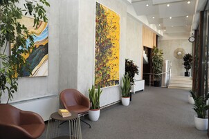 Un vestíbulo moderno con un cuadro abstracto grande, plantas en macetas y una escalera.