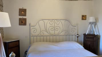 Un dormitorio con estructura de cama metálica, una mesita de noche de madera, una lámpara y un armario pequeño.