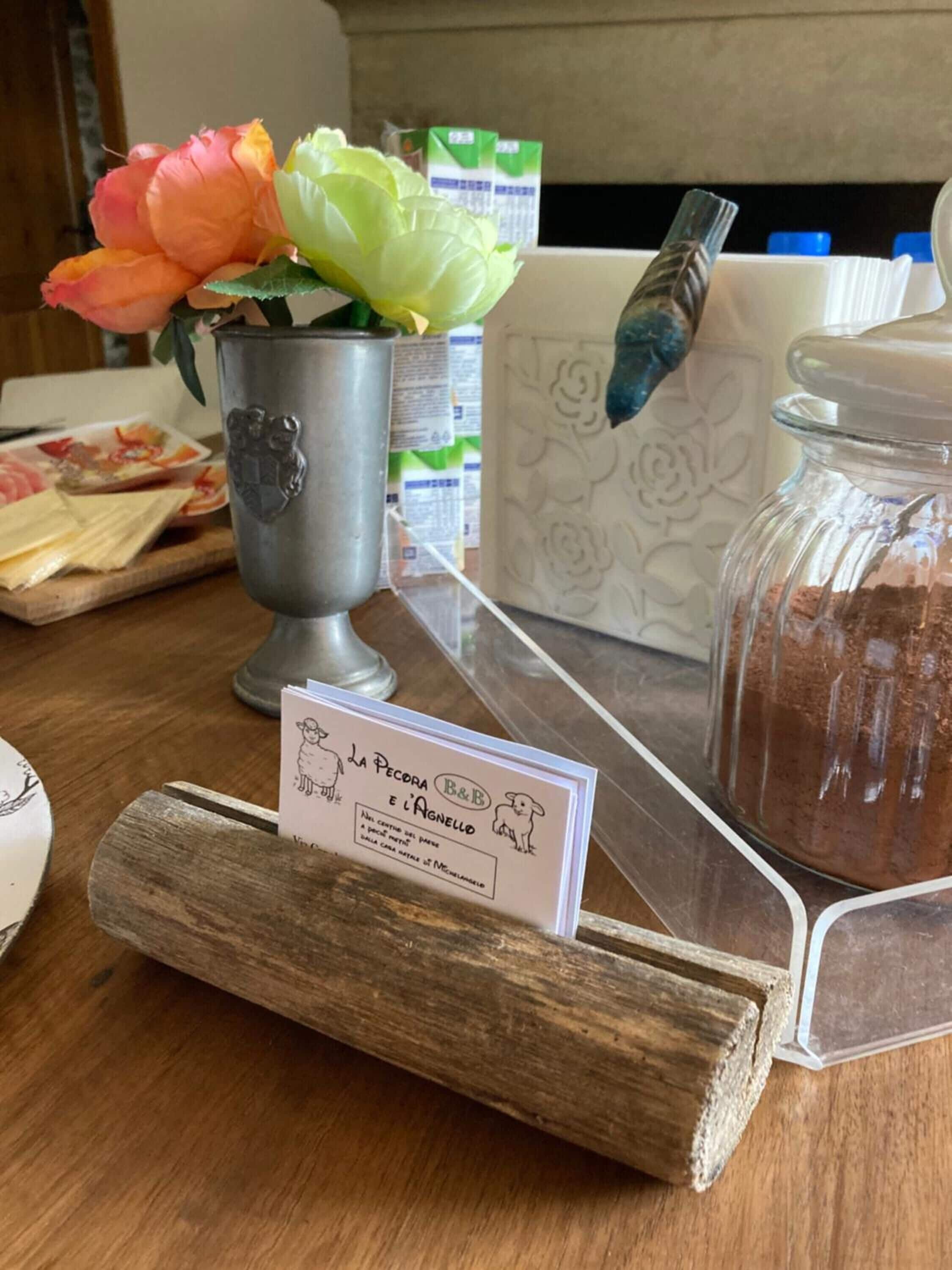A wooden counter with a metal pitcher, a jar of brown powder, and a sign with a dog illustration.