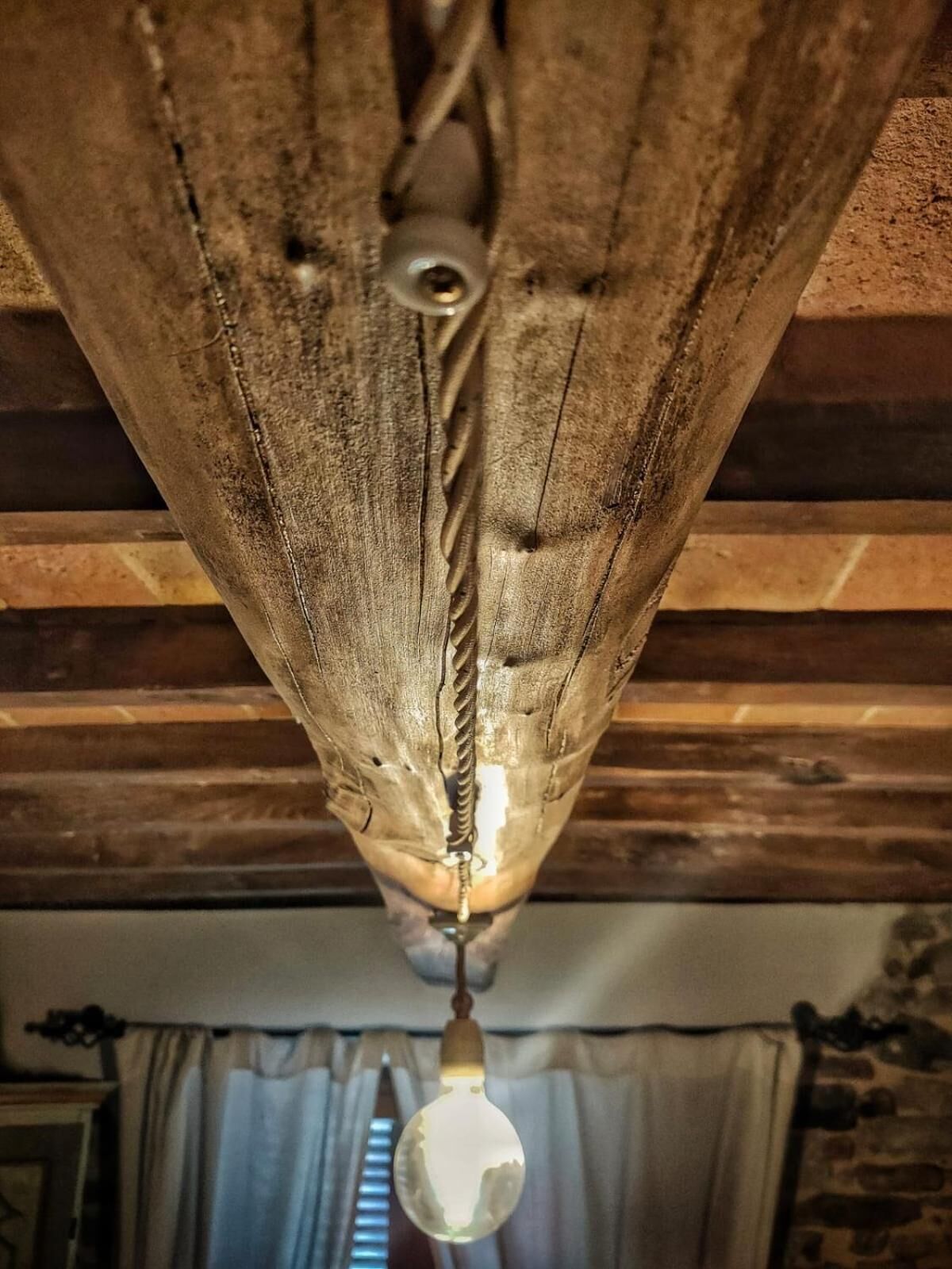 A rustic wooden ceiling with a hanging light fixture.