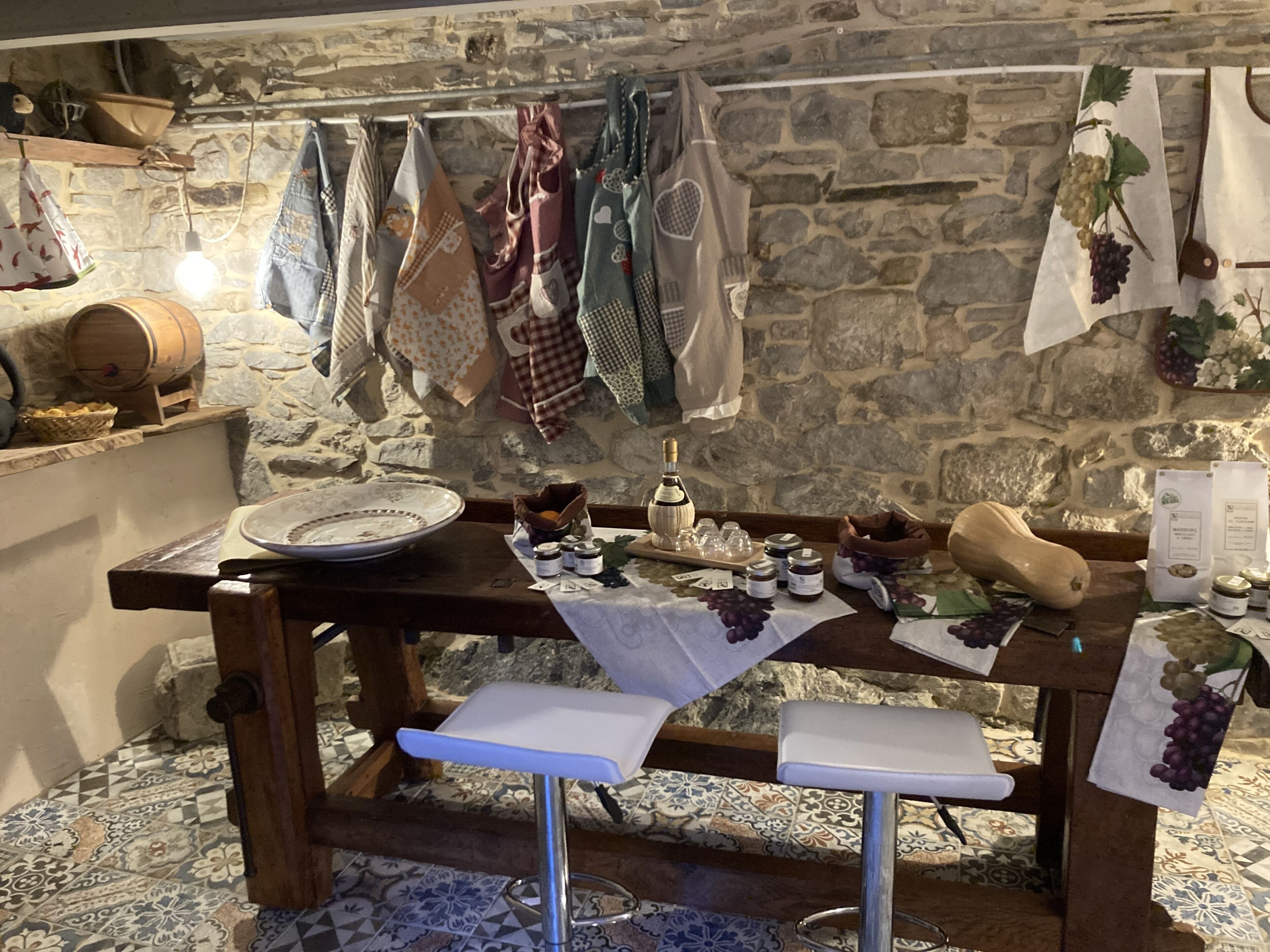 A rustic kitchen with stone walls, a wooden table, and various kitchen utensils and ingredients.