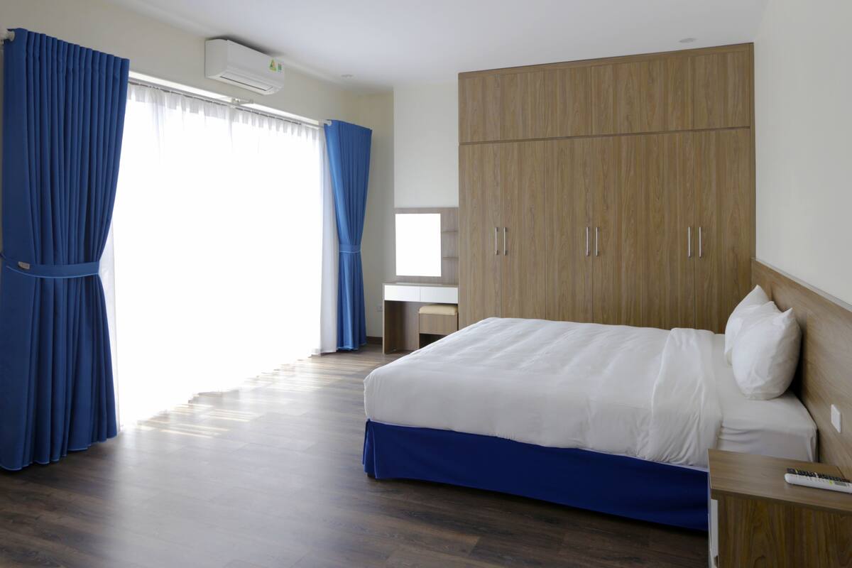 A hotel room with a bed, wooden wardrobe, and a desk.