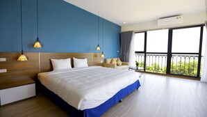 A modern hotel room with a large bed, a sofa, and a balcony with a view. - Minh Quan Building (Vinh Phuc)