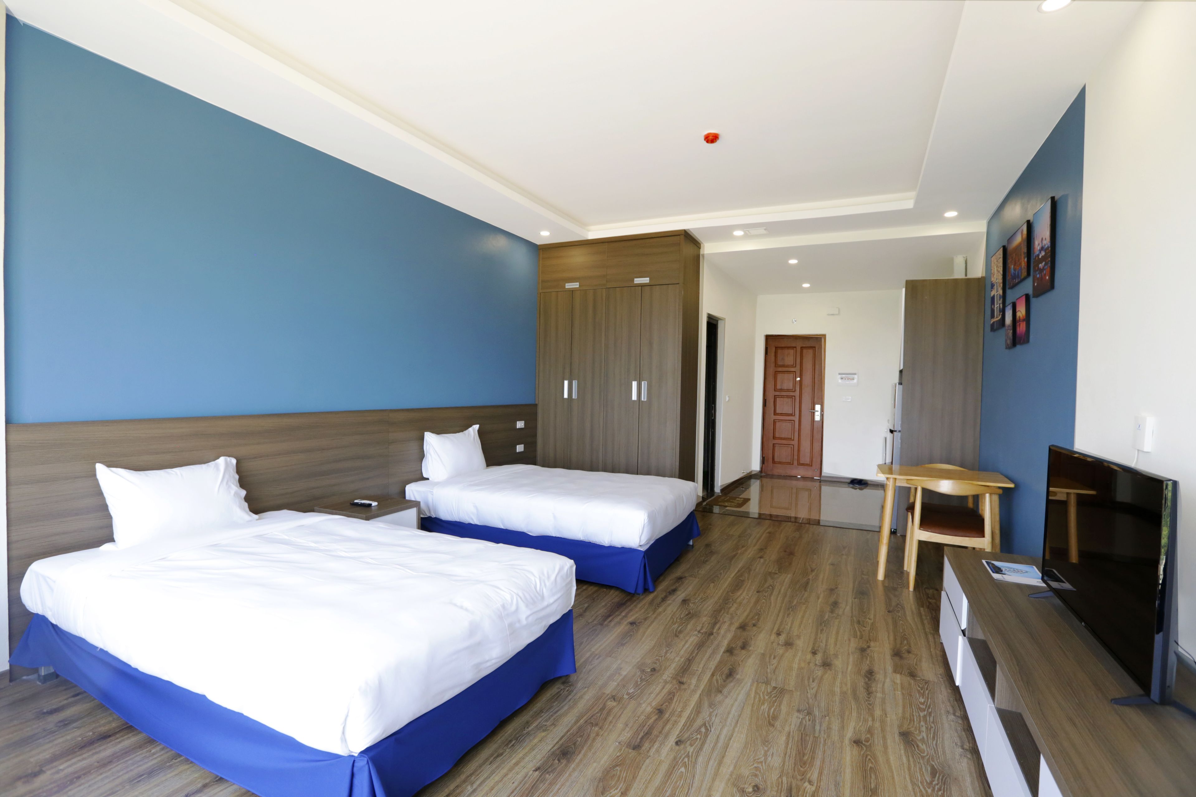 A hotel room with two beds, a desk, a TV, and a wardrobe.