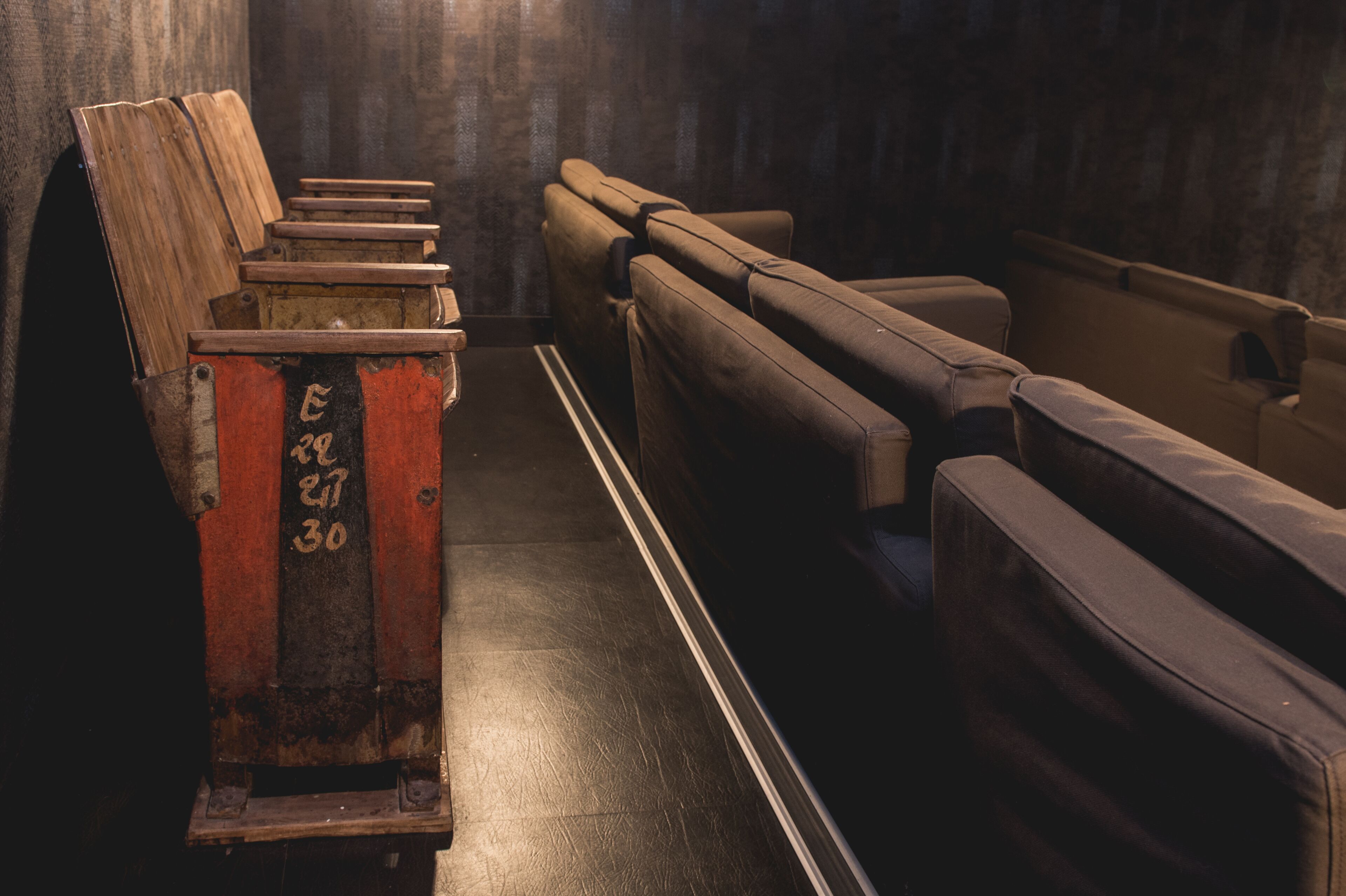 A row of wooden benches in a dimly lit room with a textured wall.