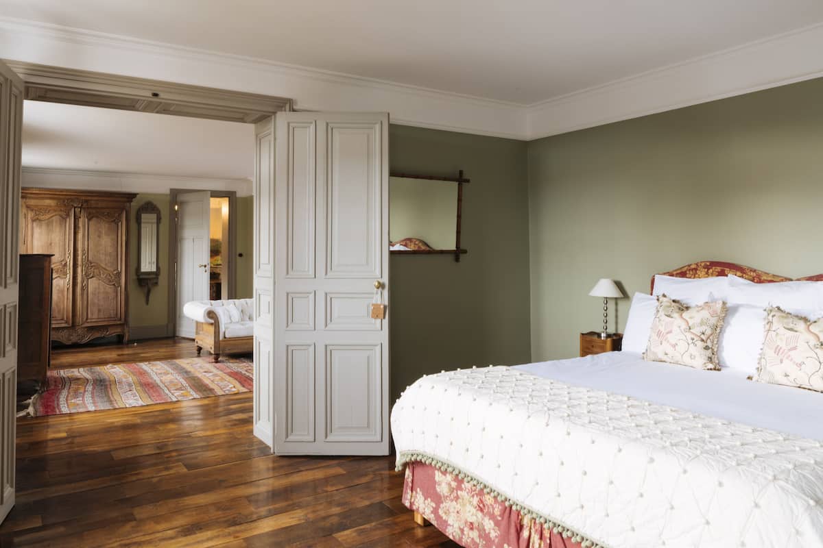 Un dormitorio con una cama grande, un armario de madera y una puerta que da a otra habitación.
