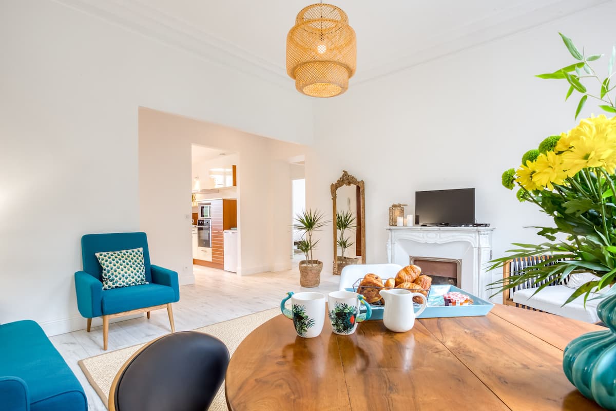 A living room with a wooden coffee table, a blue armchair, a fireplace, and a television.