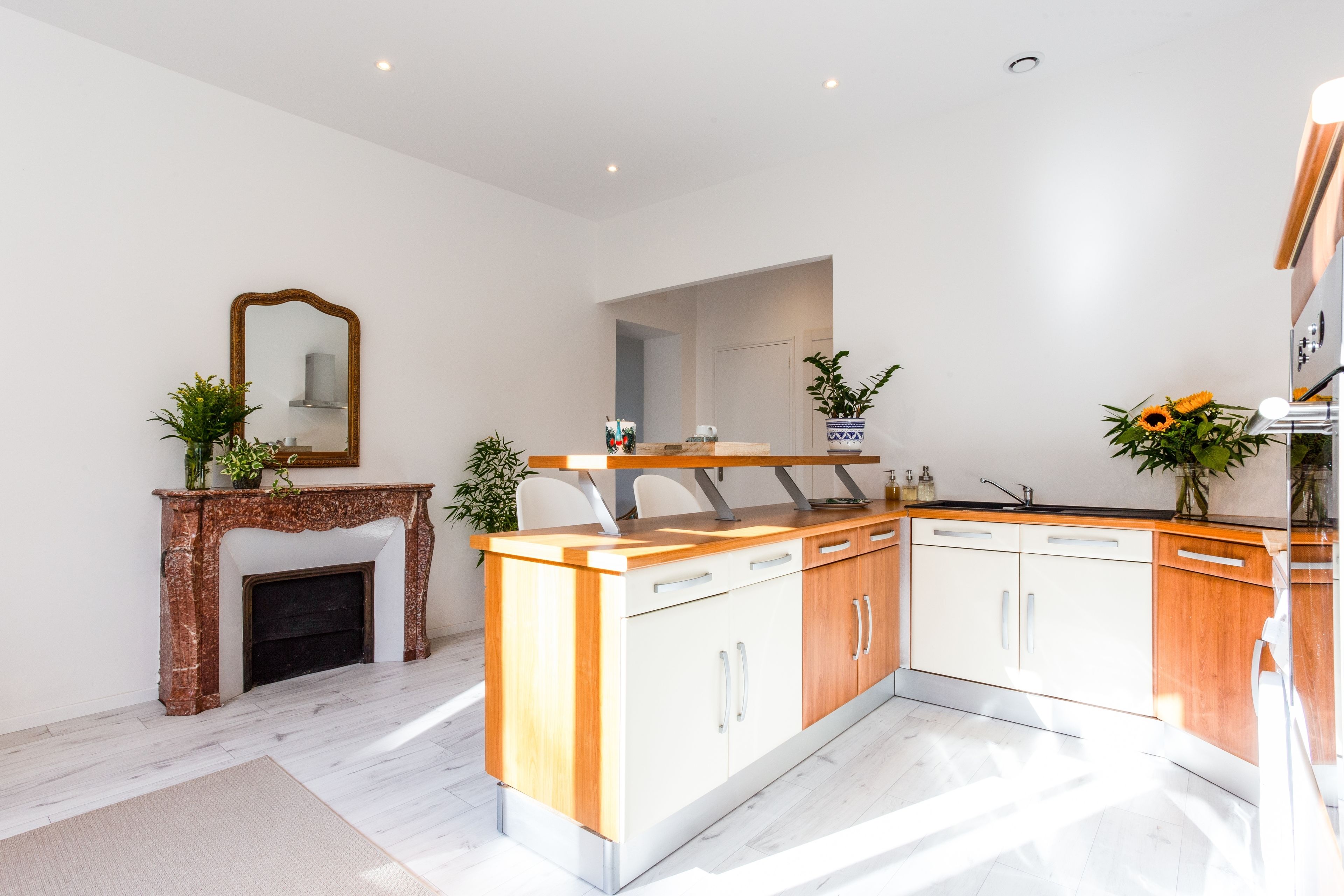 A modern kitchen with a marble fireplace, wooden cabinets, and a built-in oven.