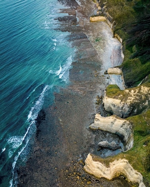 A coastal landscape with rocky cliffs and a beach. - Château Côte de Nacre (Ver-sur-Mer)
