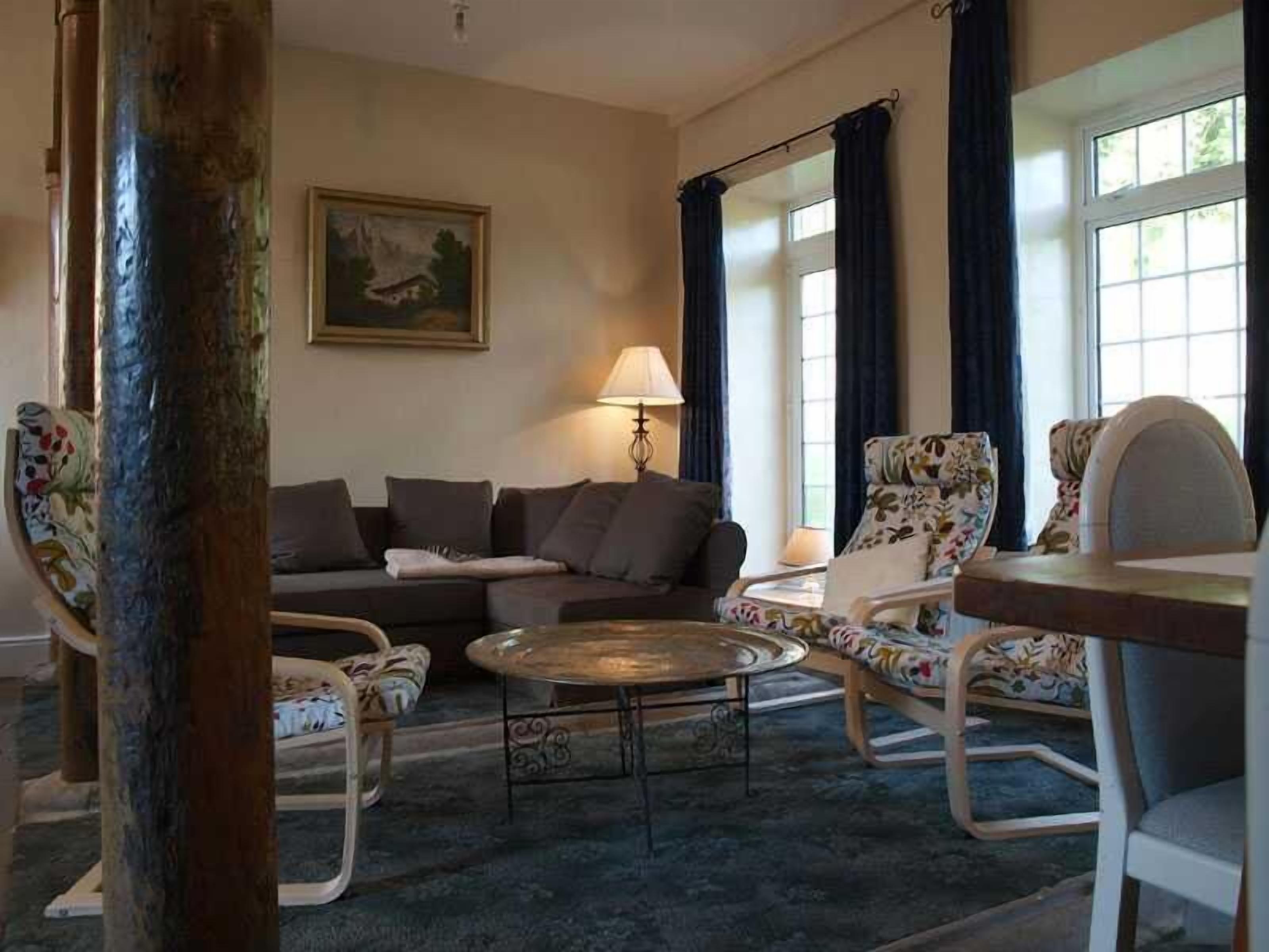 A living room with a sofa, two armchairs, a coffee table, and a painting on the wall.
