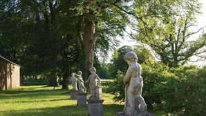 Un jardín con estatuas clásicas sobre pedestales.