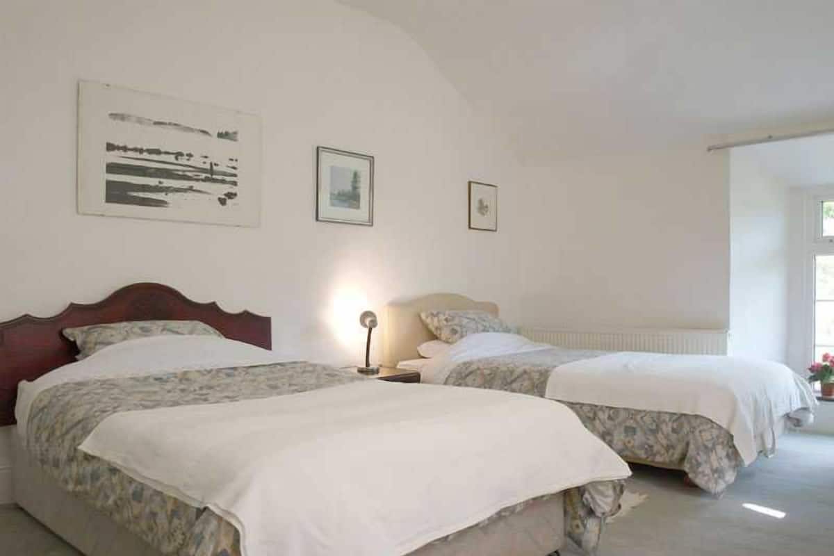 A bedroom with two beds, a nightstand, and a radiator.