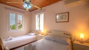 Una camera da letto con due letti, una ventola a soffitto e un quadro appeso al muro.