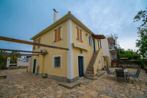 Un edificio giallo con patio in pietra, una scalinata e posti a sedere all'aperto.
