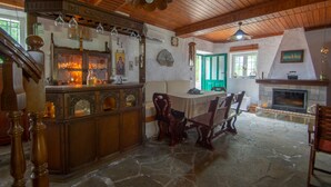 Un interno rustico con pavimento in pietra, soffitto in legno, camino e un'area bar con bicchieri.
