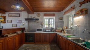 Una cucina con mobili in legno, un forno a microonde, un piano cottura e una finestra con persiane.