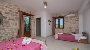 A room with two beds, stone walls, and a view of the outdoors. - Villa Windmill Sunset (Zakynthos)