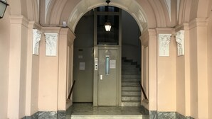 Una escalera de mármol que conduce a una puerta, con un aplique arriba.