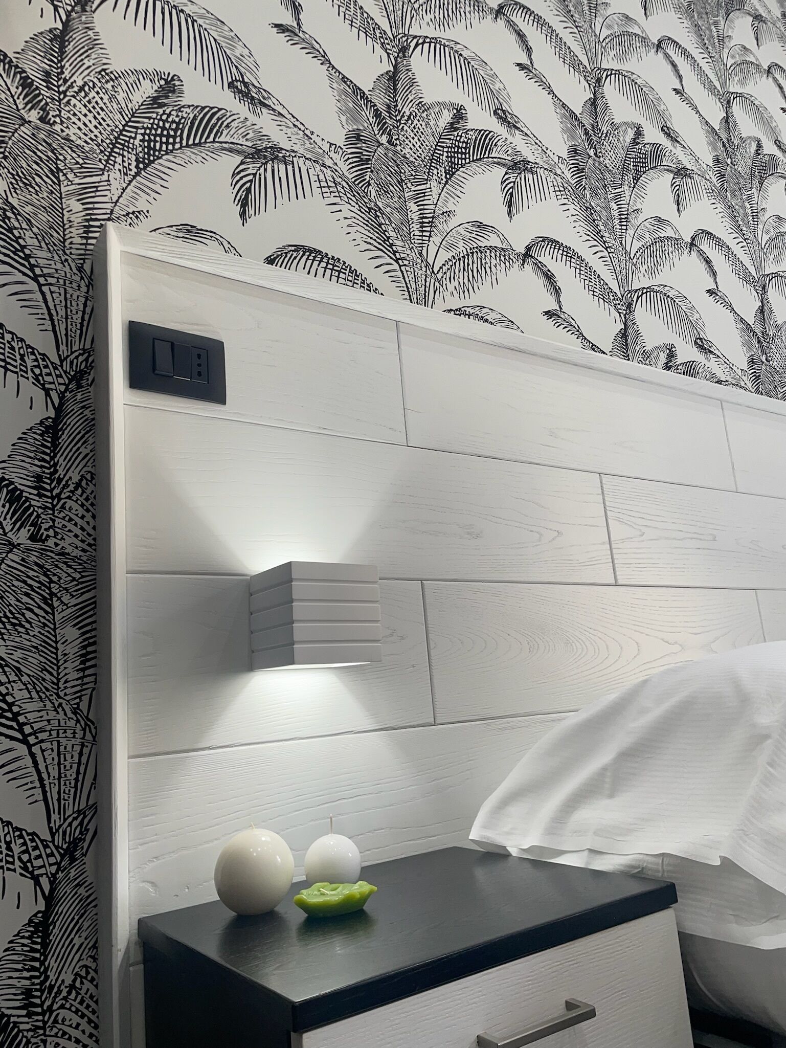 A modern bathroom with a white tiled wall, a black countertop, and a white towel hanging on the wall.