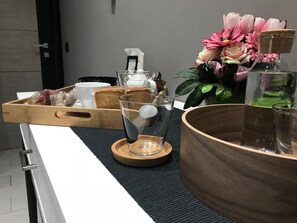 Una encimera de cocina con una bandeja de madera que contiene pan, un vaso y un recipiente pequeño.
