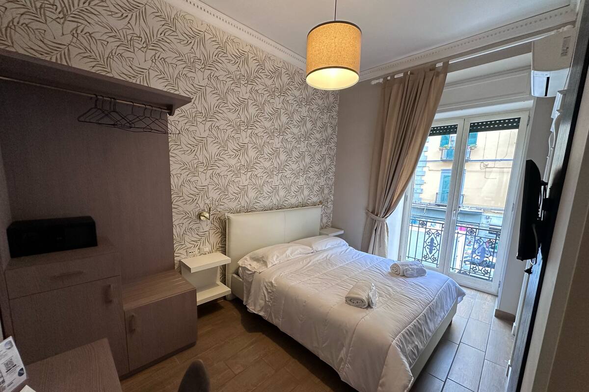 Una camera da letto con un letto, un comodino e una lampada a sospensione.