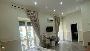 Habitación de hotel con una cama grande, un escritorio, una silla, un equipo de aire acondicionado y un televisor en la pared.