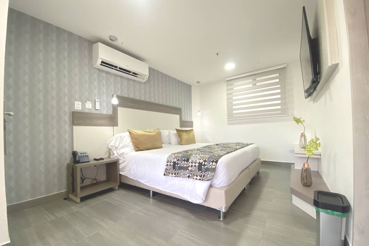 A modern hotel room with a large bed, bedside tables, a desk, and a TV mounted on the wall.